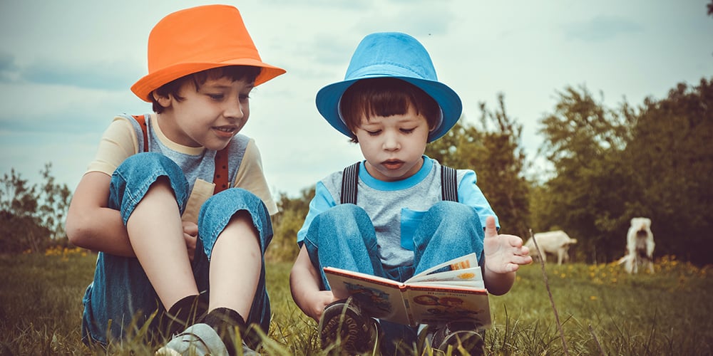 children reading a book in a field