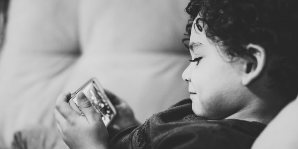 young boy using mobile phone on the sofa