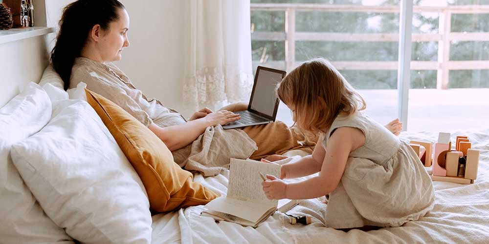 millenial parent sitting with child in the bed