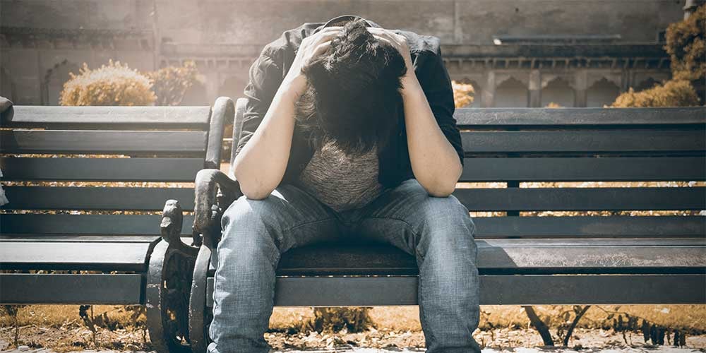 boy with head down on a bench