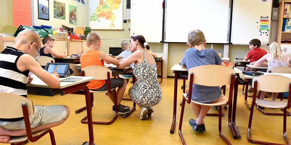 learning-at-schoolclassroom with teacher helping student