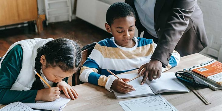 teacher correcting a child work at a desk