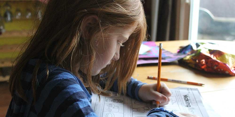 niña estudiante haciendo deberes desde casa unschooling