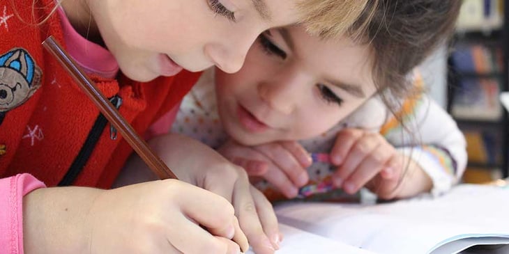 children writing at a desk