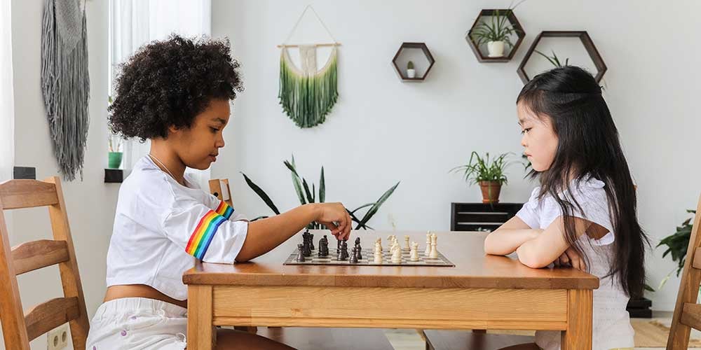 two girls playing a board game at the table