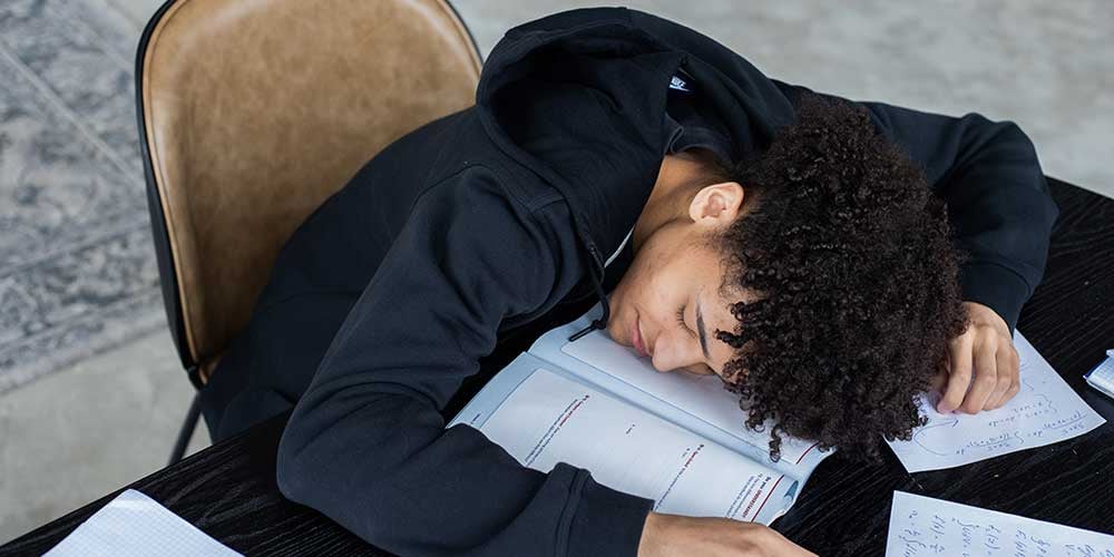 boy lying on book from the stress of exams