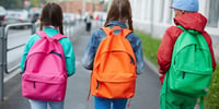 three children wearing schoolbags