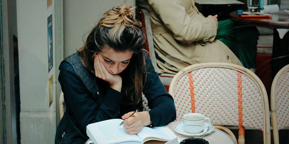 girl doing homework in a cafe