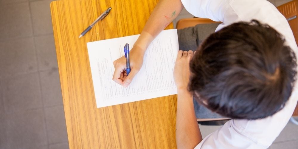 student writing exam at desk