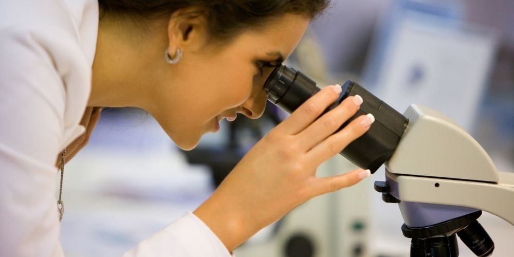 female scientist looking in microscope