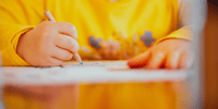 small boy in yellow jumper drawing a mind map