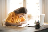 girl sitting at a table doing homework