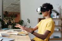 child sat at a desk using VR goggles