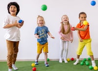 Four children laughing and playing with balls