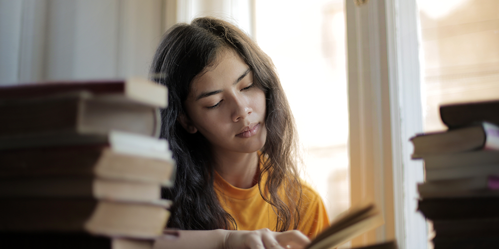 girl looking tired while reading a book
