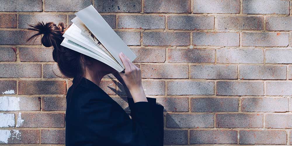 girl with book over her face 