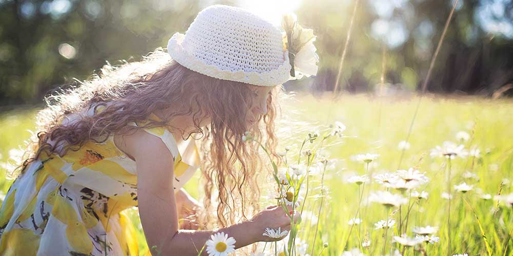 girl smelling flowers in a field 