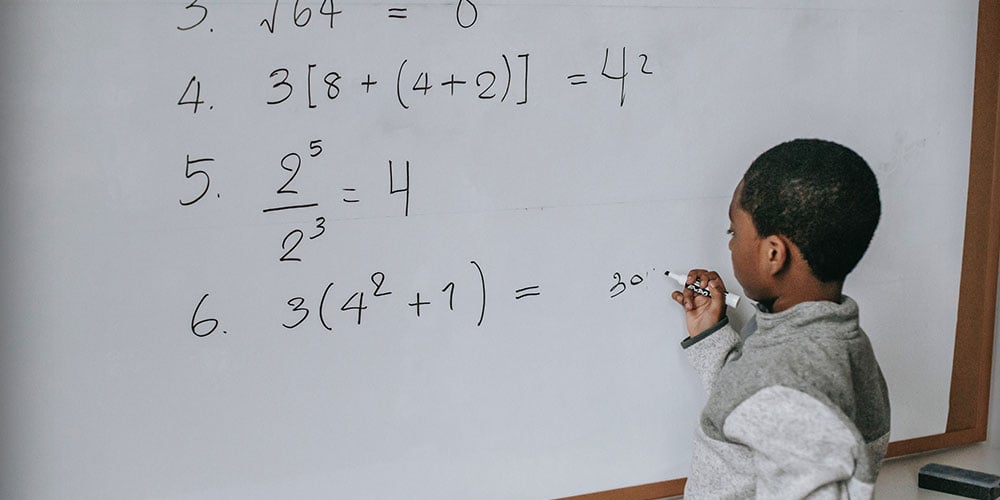 child doing maths on a board