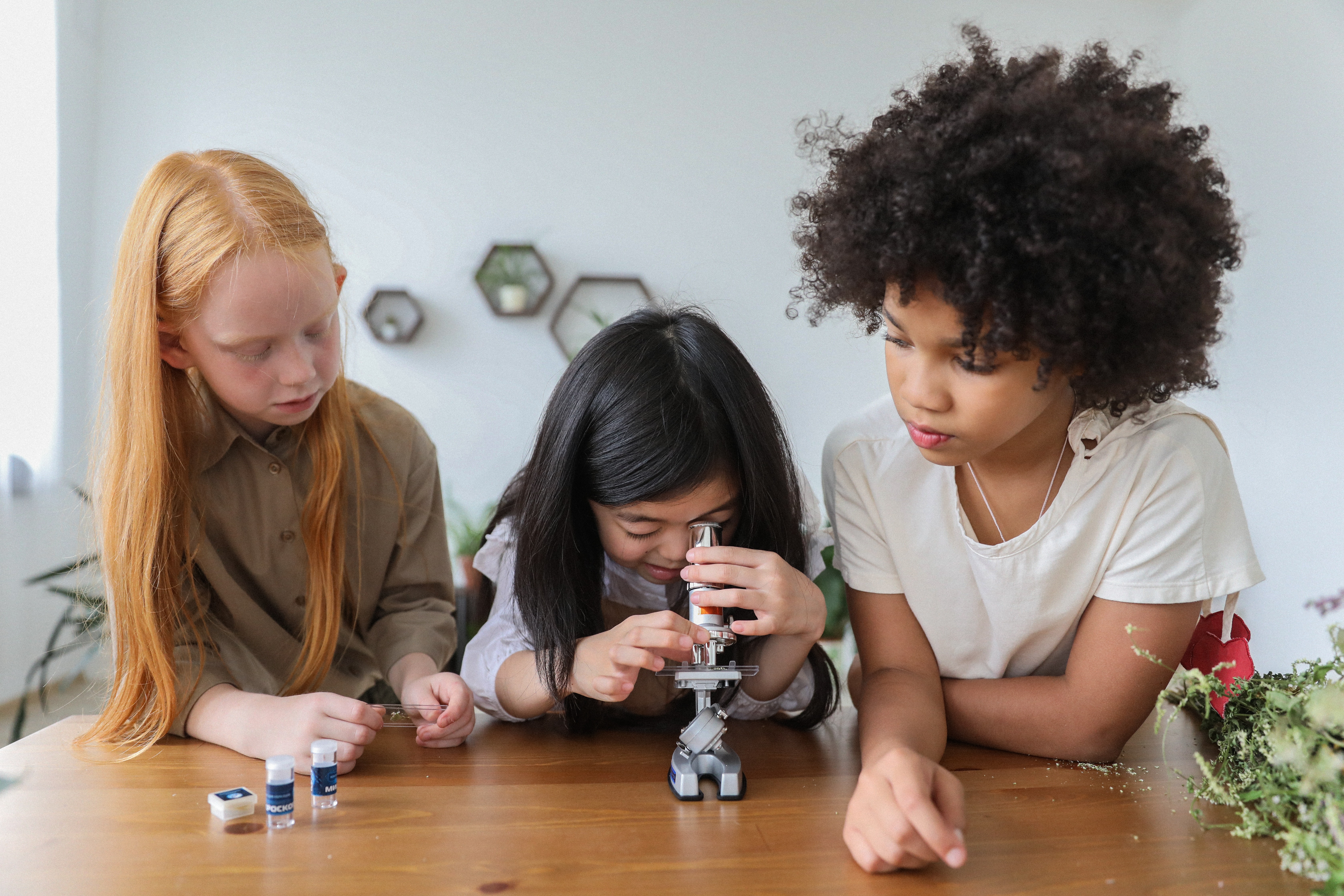 three girls looking through a microscope