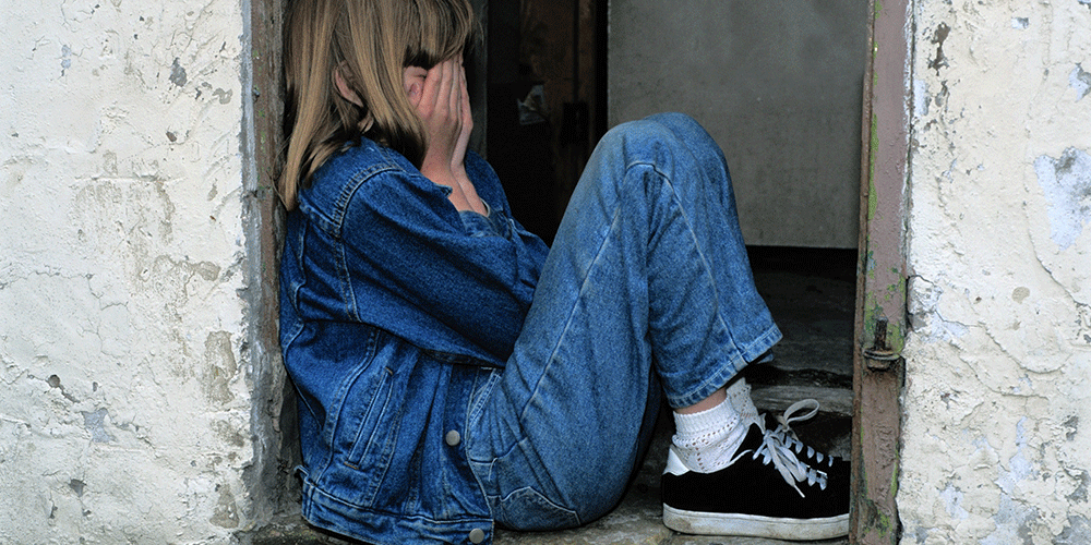 difficult teenage sitting crying on a windowsill